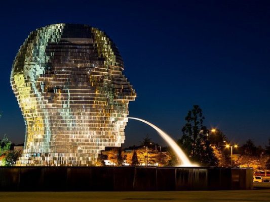 Đài phun nước Metalmorphosis hình đầu người xoay tròn bằng kim loại. Tác phẩm gồm các mảnh kim loại phản chiếu ghép thành gương mặt khổng lồ có thể xoay chuyển, tạo hiệu ứng nước chảy xuyên qua các lớp cấu trúc.